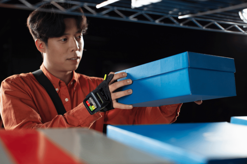 Male warehouse worker wearing a hand device for warehouse